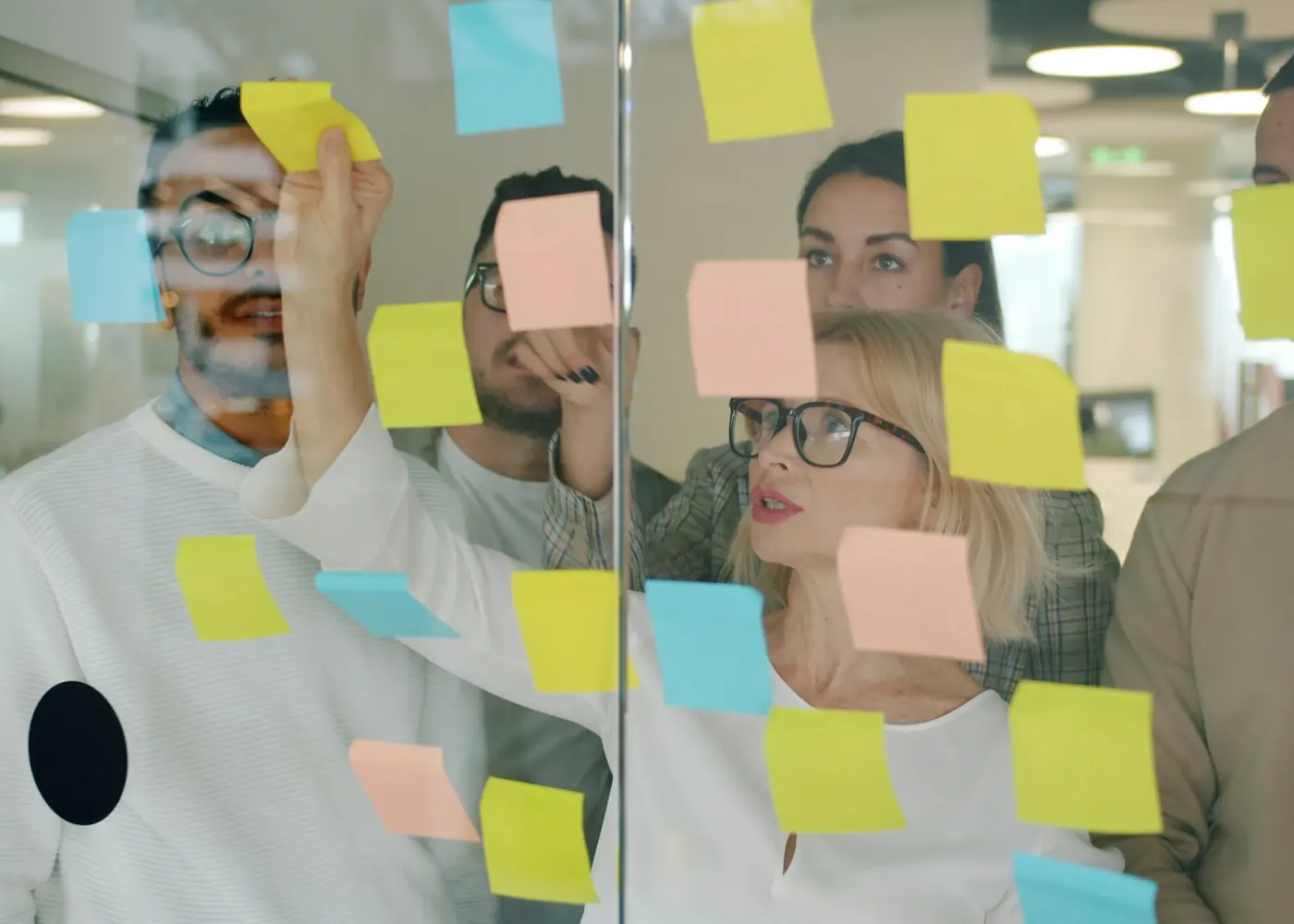A team working with sticky notes on a glass wall